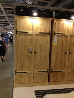 two wooden doors are open on display in a room with people walking by and one person is looking at the floor