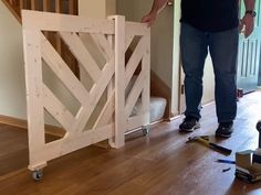 a man standing next to a wooden gate on top of a hard wood floor