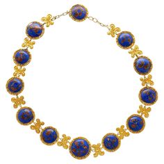 Lapis Necklace in 14k & 18K Gold. This Riviera styled necklace features 12 cabochon-cut lapis gemstones, each measuring 19–16 mm, and exhibits gold detailing within each stone, enhancing the royal blue hue. The necklace is crafted from 14K & 18K yellow gold, and surround each lapis stone with a textured design. The gold is also crafted into paisley art nouvea design between each stone, adding a feel of historical elegance to the piece. Comfortably sized at 17 inches and weighing 71.02 grams, this substantial chain necklace is a perfect gift to add to your jewelry collection. Item Details: - Type: Necklace - Metal: 14K Yellow Gold, 18K Yellow Gold - Weight: 71.02 grams - Setting: Bezel - Size: 17 inches _______________________ Stone Details: - Lapis: 12 Cabochon cut Lapis, 19-16mm (each) __ Motif Art Nouveau, Motifs Art Nouveau, Lapis Stone, Lapis Necklace, Paisley Art, Blue Lapis, Textured Design, Metal Necklaces, Gold Details