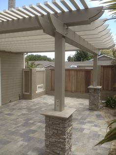 an outdoor patio with stone pillars and a pergolan roof