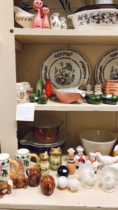 there are many plates and bowls on the shelves in this display case that is filled with figurines