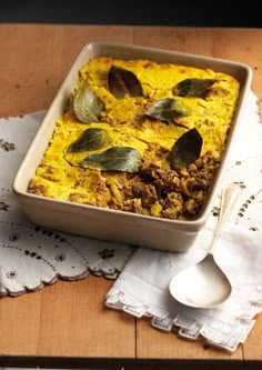 a casserole dish with meat and vegetables in it on a napkin next to a spoon