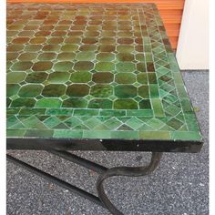 a table with green and brown tiles on it's top, sitting in front of a door