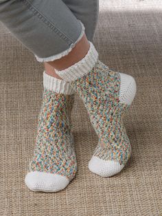 the feet of a person wearing knitted slippers with colorful sprinkles