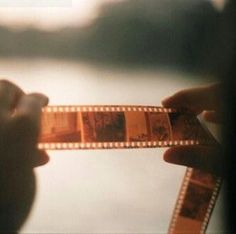 a person holding up a film strip with pictures on it's sides and the film being held by their hands