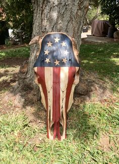 a cow skull with an american flag painted on it's side sitting under a tree