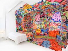 a bed with graffiti on it in front of a wall covered in papers and pictures