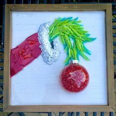 an ornament and christmas decoration made out of paper on a white board with a wooden frame