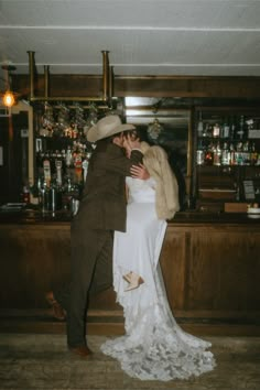 a bride and groom kissing in front of a bar