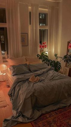 a large bed sitting in a bedroom next to a window filled with plants and candles