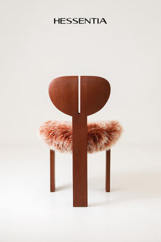 a wooden chair with a furry seat cushion on it's back and the word hessentia above it