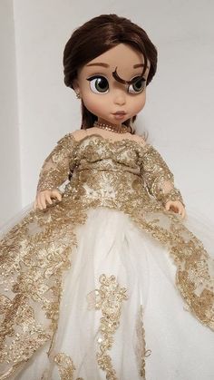 the doll is wearing a gold and white dress