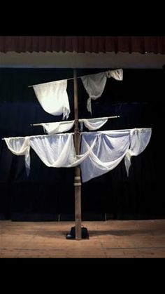 a pole with white curtains hanging from it's sides in front of a black wall