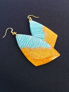 "These earrings feature the patterns of the sand and sea. On one half, pearlescent blue and white ripples move your eye back and forth and seemingly collide with an almost holographic textured golden background. They are perfect for anyone with a unique flair and anyone who cherishes the sun.  They are handmade and unique--no two have the same design. They are lightweight, which makes them a thoughtful gift for anyone who has trouble with heavier earrings. Each earring is made by hand and will have slight variations in the pattern. All of my materials are nickel-free and hypoallergenic. Reika means \"wander\" in Icelandic, and being a wanderer is crucial to my existence. As such, all of my pieces are imbued with parts of the natural world that have inspired me. It is my hope to provide thi Bohemian Gold Resin Earrings, Unique Hand Painted Turquoise Earrings, Unique Hand Painted Blue Earrings, Blue Artistic Design Drop Earrings, Summer Gold Resin Earrings, Artistic Blue Jewelry For Summer, Artsy Blue Teardrop Earrings, Unique Blue Earrings With Artistic Design, Unique Blue Earrings For Beach