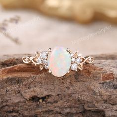 an opal and diamond ring on top of a piece of wood