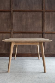 a wooden table sitting on top of a carpeted floor next to a brown wall