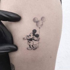 a person with a mickey mouse tattoo on their thigh holding a balloon in the air