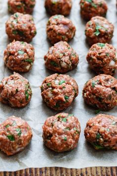 raw meatballs on parchment paper lined up in rows