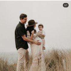 a man, woman and child standing in tall grass