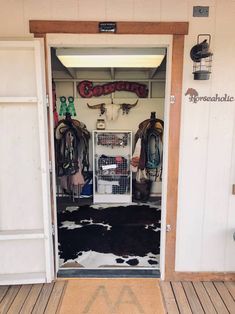 an open door to a room with several coats hanging on the wall and cowhide rugs