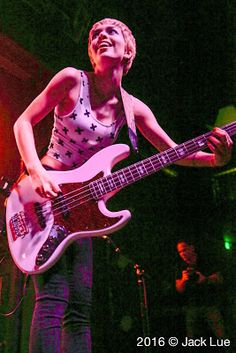 a woman playing a bass guitar on stage