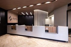 an empty reception area with wooden flooring and white counter tops, along with modern lighting