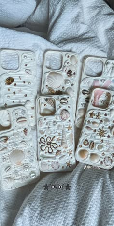 five cell phones with shells and seashells on them are laying on a bed