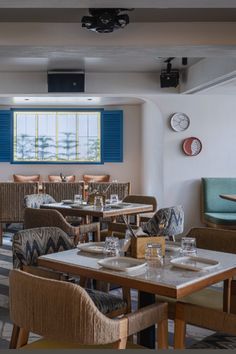 an empty restaurant with blue shutters and wooden tables set up for two people to eat