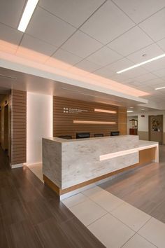 an empty reception area with wood paneling and white marble counter top, along with hard wood flooring