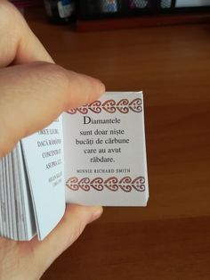 a person holding up a business card on top of a wooden table