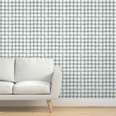 a white couch sitting in front of a blue and white checkered wallpapered background