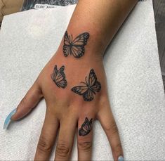 a woman's hand with three butterflies on it and one is showing the middle finger