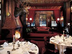 a dining room with tables, chairs and an elk head hanging from the ceiling above