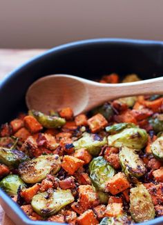 brussel sprouts and carrots in a pan with a wooden spoon