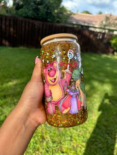 someone holding up a cup with winnie the pooh and friends on it in their hand