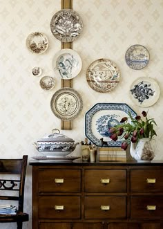 there are many plates on the wall above this dresser