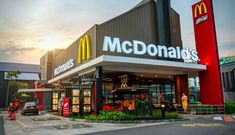 a mcdonald's restaurant in the middle of a street with people walking around it