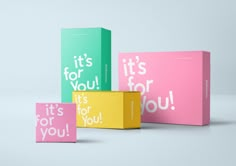 three colorful boxes with the words it's for you printed on them, one pink and one green