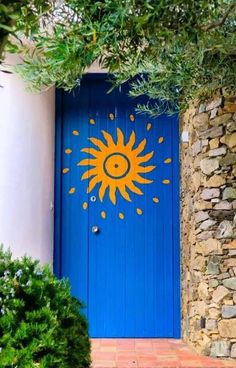 a blue door with a smiley face painted on it's side and surrounded by greenery