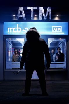 a man standing in front of a atm with his back turned to the camera and holding an umbrella