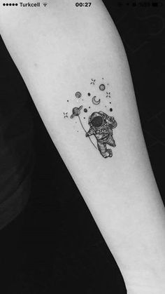 an astronaut tattoo on the left inner forearm and arm, with stars in the sky