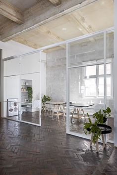 an empty room with tables and chairs in the center, surrounded by glass doors that lead to another room