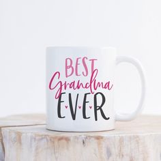 a white coffee mug with the words best grandma ever on it sitting on a tree stump