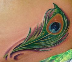 a woman's stomach with a peacock feather tattoo on it