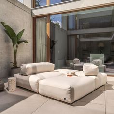 a white couch sitting on top of a cement floor next to a large glass window