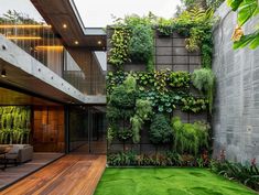 an outdoor living area with grass and plants on the wall, surrounded by wooden decking