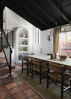 a dining room table and chairs in front of a window with an open bookcase