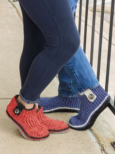 a person standing next to a fence wearing crocheted slippers and blue jeans