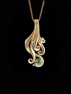 "Imagine swimming in a clear pool beneath a cascading waterfall. One of my favorite design inspirations are waves and the undulating curves of water. The pendant is cast in solid 14K gold, is 1-1/4\" (32 mm) long and is set with a 4 mm Sandwana Emerald from Zimbabwe. This fluid piece is beautifully sculpted both front and back.  All Marty Magic Jewelry is packaged in a beautiful box, embossed with the gold foil Marty Magic dragon logo. Perfect for any occasion. Designed in Santa Cruz, California by Marty Magic.  Made in the U.S.A." Luxury Gold Wavy Jewelry, Unique Gold Swirl Jewelry, Modern 14k Gold Wavy Jewelry, Gold Wave Necklace, Yellow Gold Wavy Jewelry With Polished Finish, Dragon Logo, Magic Jewelry, Magic Dragon, Wave Pendant