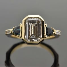 14kt Yellow Gold Diamond and Green Sapphire Ring. This geometric design features a large bezel-set emerald cut diamond with a trillion cut green sapphire and a diamond baguette on each side. This item is a custom order only. Price is for the ring setting only. The stones will be priced separately. The completion of the item will take about 20 - 30 days. You can use your own center stone or request a quote for stones from our inventory. Please provide the ring size or we will make it an average s Luxury Emerald Baguette Cut Bezel Set Ring, Bezel Set Engagement Ring, Vintage Art Deco Rings, Saphir Ring, Green Sapphire Ring, Diamond Baguette, Future Engagement Rings, Emerald Cut Diamond, Deco Engagement Ring